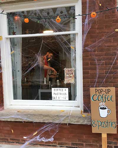 Looking through the window decorated for Halloween at coffee being poured