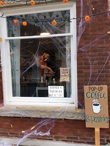Looking through the window decorated for Halloween at coffee being poured